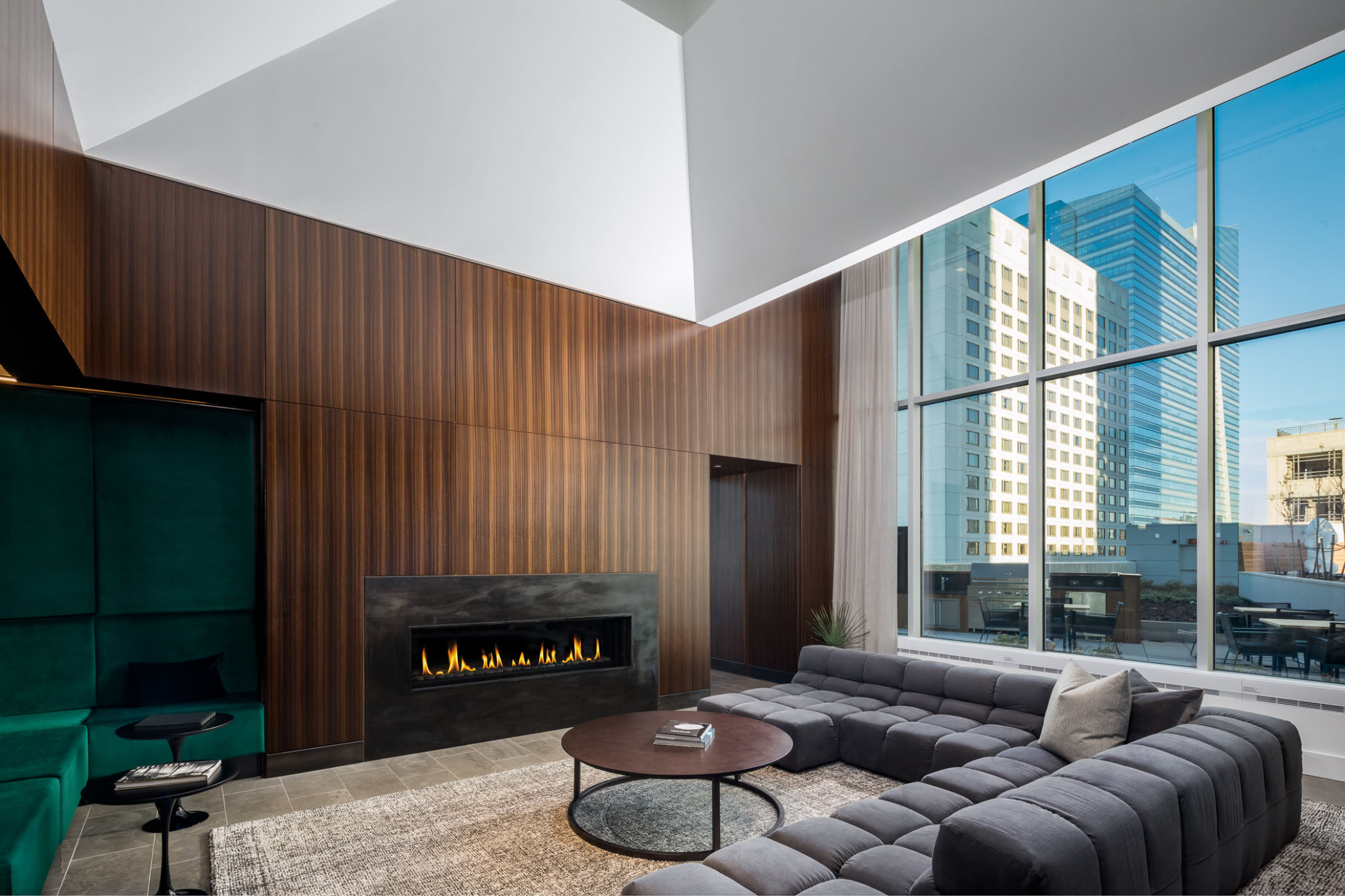 resident lounge with giant wall of window fire place and luxury gray couch